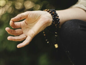 photo of right hand in chin mudra position with large bead bracelet