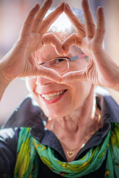 Cute senior old woman making a heart shape with her hands and fingers